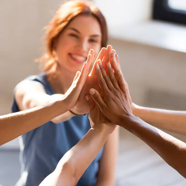Cheerful diverse young girls sitting together in sports studio before starts training giving high five feel happy and healthy, close up focus on hands. Respect and trust, celebration and amity concept